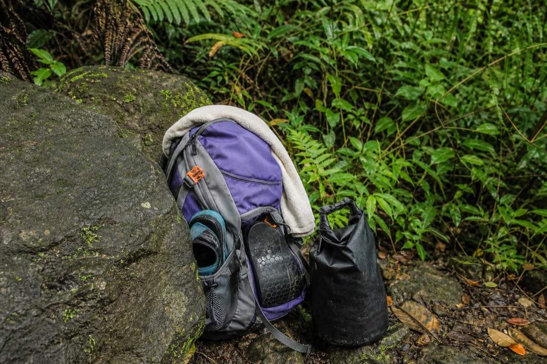 Daypack with towel, water shoes and dry bag packed for a guided waterfall swim near Hilo