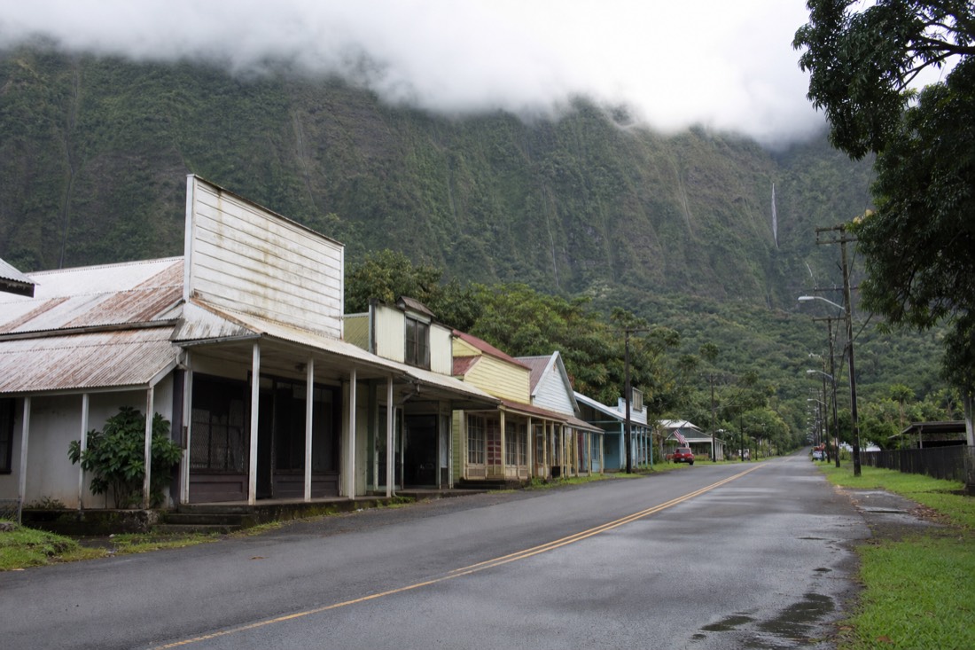 Quiet main street of an old Hamakua plantation town with wooden false-front buildings under low cloud