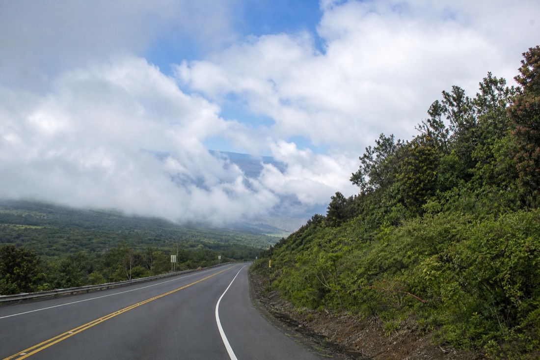 Wide empty highway crossing the high lava saddle between Mauna Kea and Mauna Loa with cloud sitting at road level