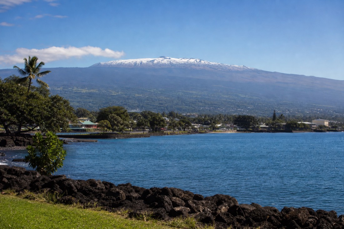 Hilo Bay seen from the seawall on a clear morning with the snow-dusted summit of Mauna Kea rising behind the town
